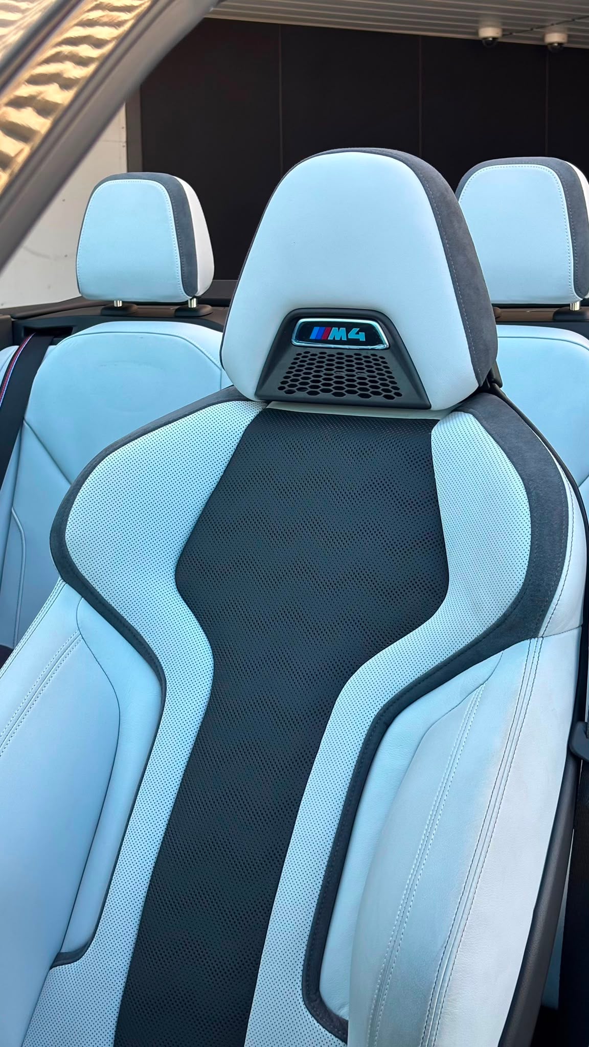 Light-blue BMW M4 seats with black inserts and M4 badges