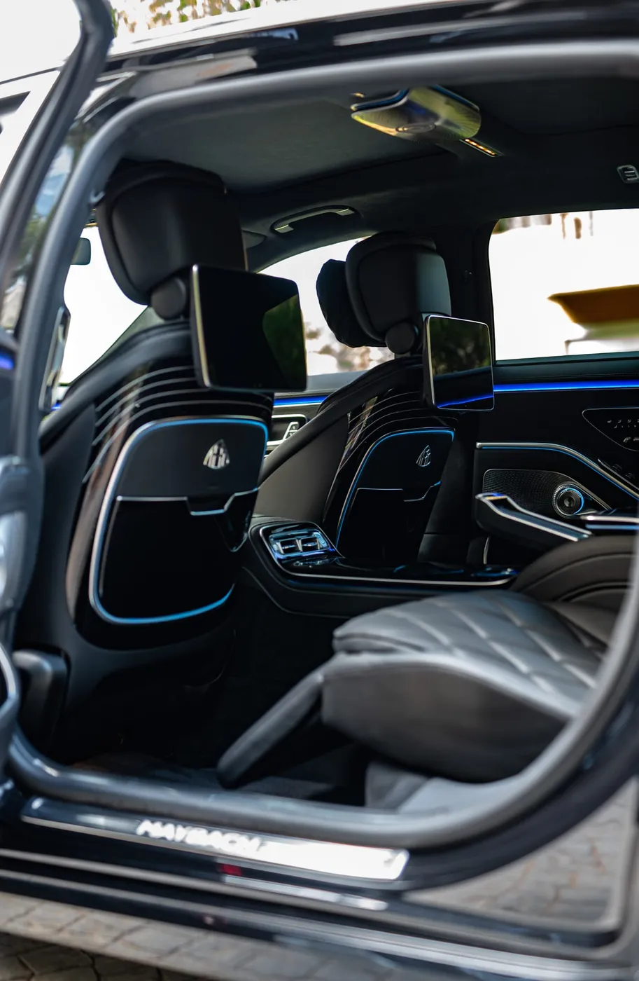 Maybach S 680 rear cabin viewed through an open passenger door, showing seating, rear screens and footwell.