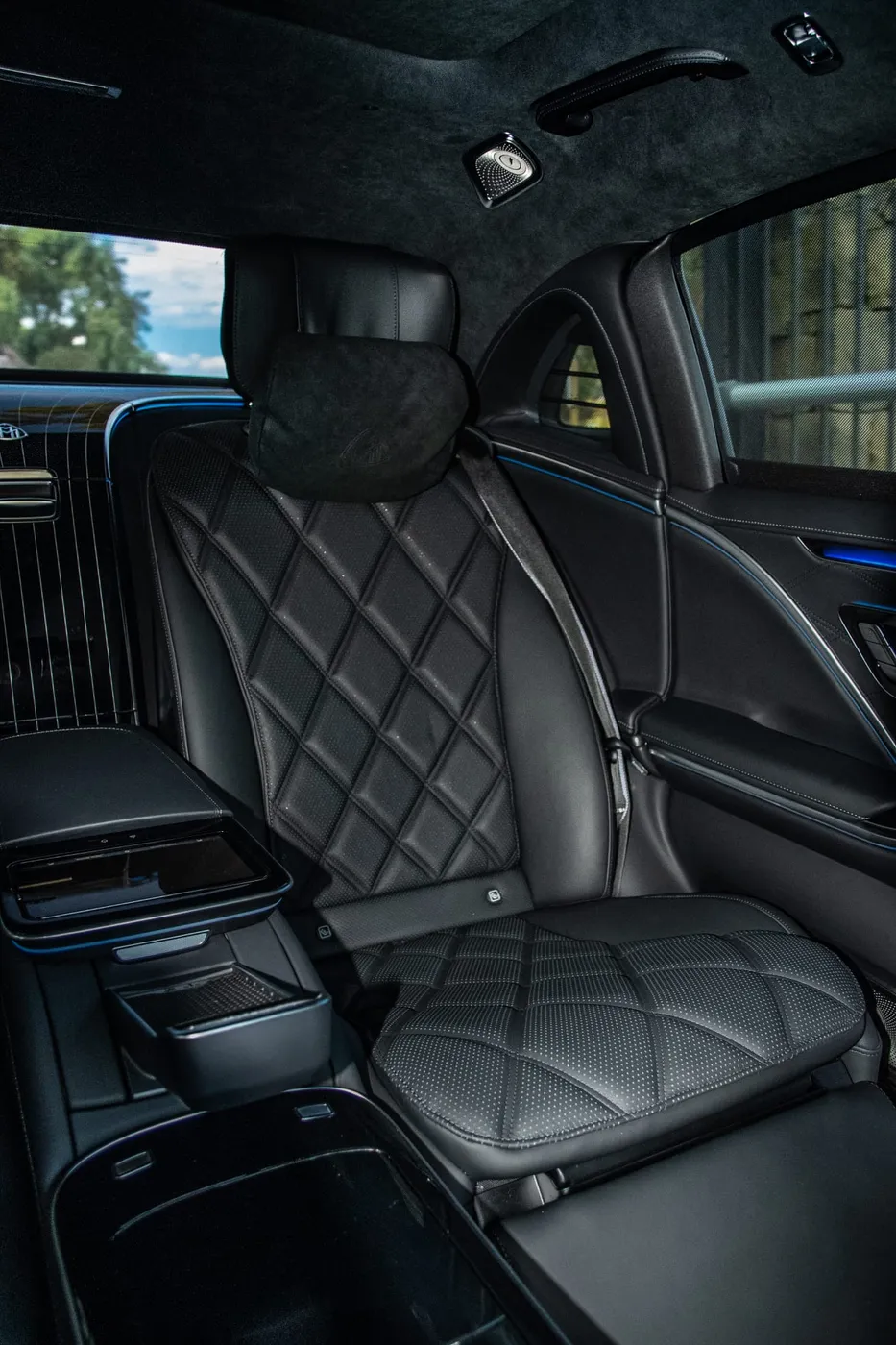 Quilted black rear passenger seat with a headrest cushion, centre armrest and blue cabin lighting in the Maybach S 680.